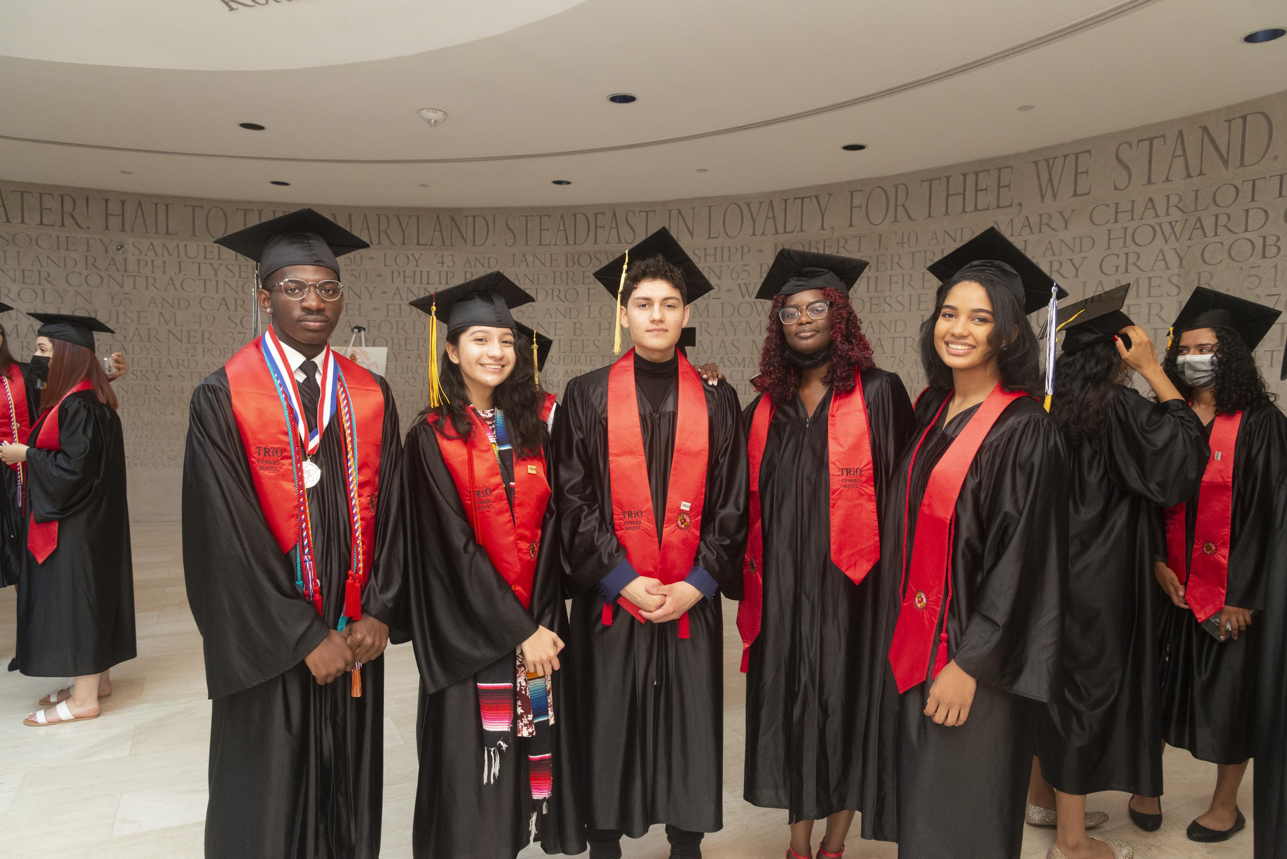 five grads in cap and gowns